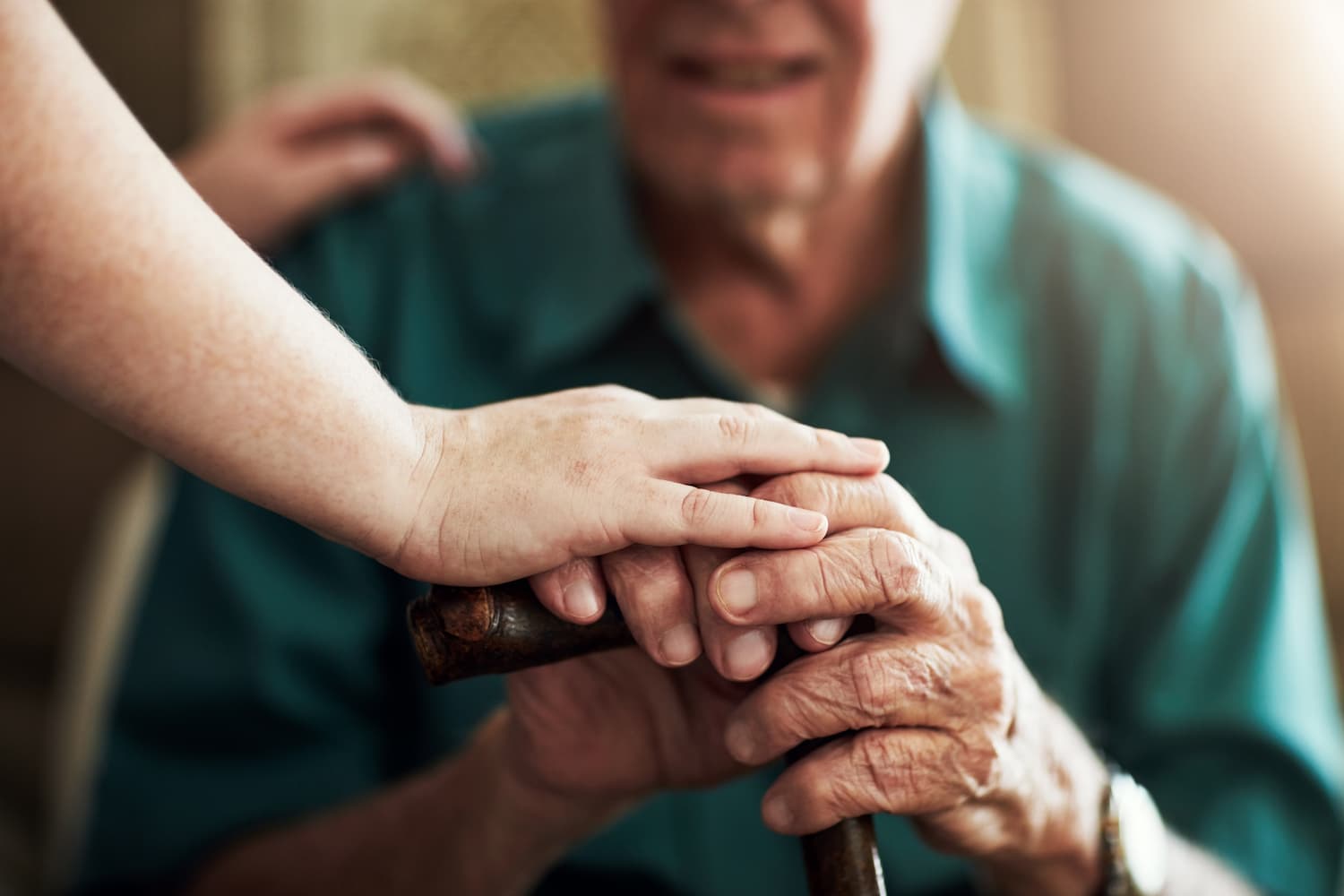 An elderly man with a gentle expression holds hands with a young woman, symbolizing connection amid Alzheimer's Disease.